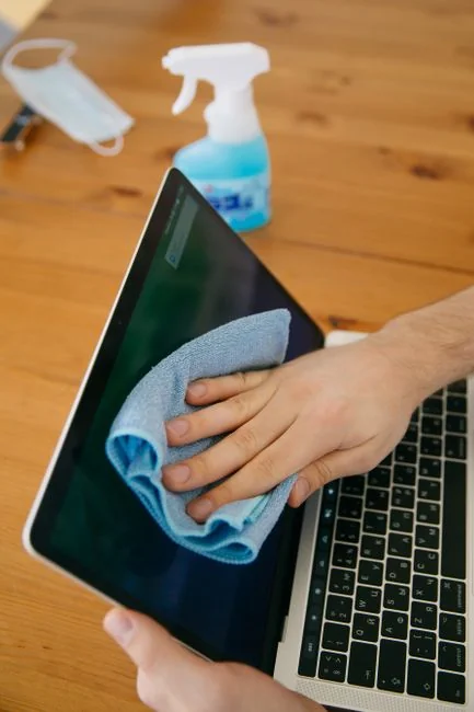 A person in protective gear disinfecting an office desk with fumigation equipment in daylight.